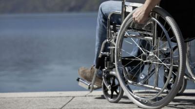 Man in wheelchair sitting by water.