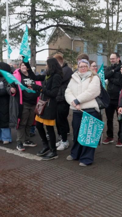 Teachers stood with banners outside a school