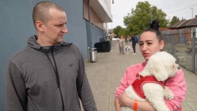 Lukasz and Agnieszka, holding dog, giving interview