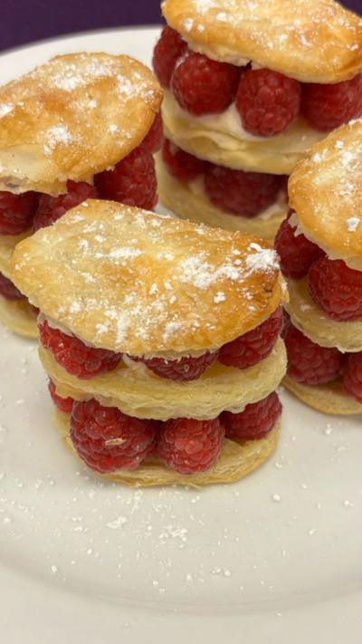 Close up of three-tired puff pastry circles with raspberries in the middle of each layer