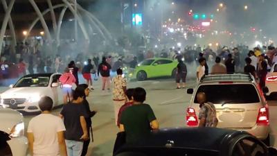 A screengrab from footage shows a stunt driver blocking an overpass in Atlanta, while pedestrians watch