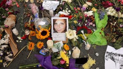 Flowers, candles and chalk-written messages surround a photograph of Heather Heyer on the spot where she was killed