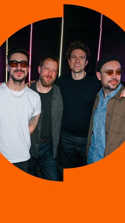 The three members of Mumford and Sons stand with Greg James in the Radio 1 studio