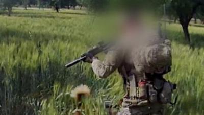 Solder pointing gun at person lying on the ground