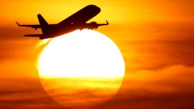 a plane flies into the sunset