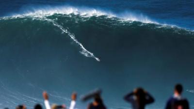 A surfer rides a large wave at Praia do Norte in Nazare