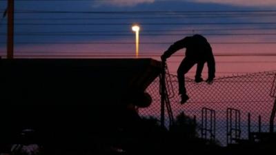 Migrant scaling fence in Coquelles