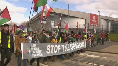 Gaza protestors holding a 'stop the genocide' banner and Palestinian flags march on the Emirates Arena in Glasgow.