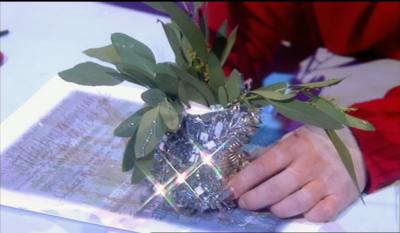 Close up of a Christmas flower arrangement in a tin, covered with tinsel