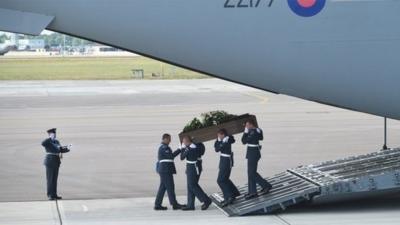 The coffin of Adrian Evans is taken from the RAF C-17 carrying the bodies of eight British nationals killed in the Tunisia terror attack at RAF Brize Norton