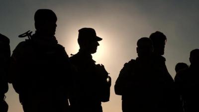 Silhouettes of soldiers looking at a mass grave