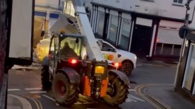 A cash machine being removed from a wall and lifted on to a getaway pickup truck.