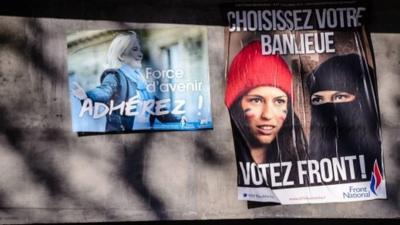 An election campaign poster for French far-right Front National (FN) party reads "Choose Your Suburb - Vote Front" and features a Muslim woman, wearing an islamic veil and with the French national colours painted on her face.