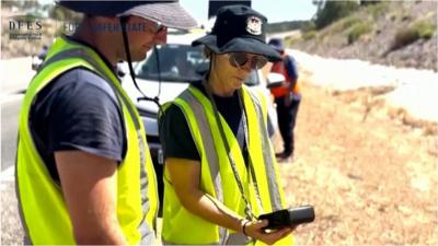 Two people looking a hand held gamma ray detection device