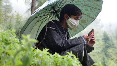 Student looks at his phone on a mountainside