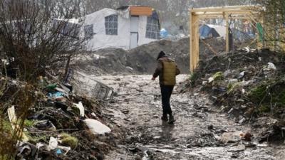 A man walks through the Jungle migrant camp in Calais, France