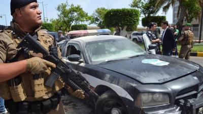 Lebanese security forces stand next to a vehicle damaged in a gun attack in Tripoli (4 June 2019)