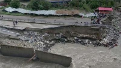 People standing on road partially destroyed by floods