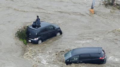 Man on top of car during floods