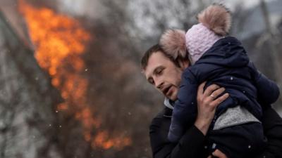 Man running with child in Irpin, 6 March 2022