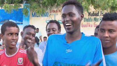 Abdunasir Mohamed in blue football shirt with supporters