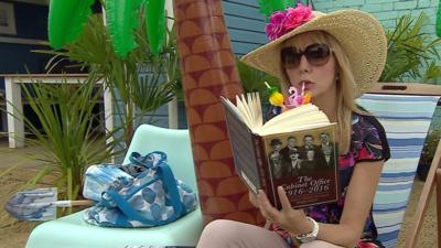 Ellie Price reading on a beach