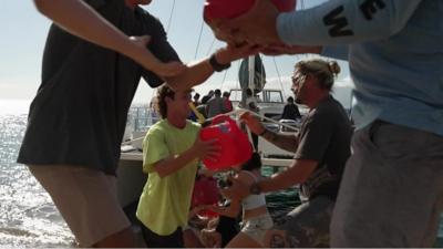 People passing items down a human chain from a boat