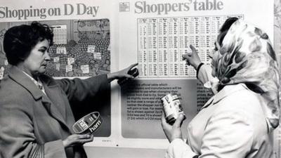 Two women looking at a conversion chart for their money