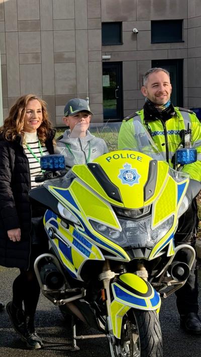 a mum and her son next to a police motorcycle and motorcyclist