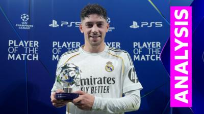 Federico Valverde smiles to camera and holds up a trophy in champions league 