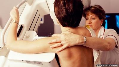 Radiologist positioning a woman for a mammogram