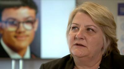 Viv Clifford sits in front of a picture of Ramarni Crosby