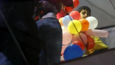 Boy holding bunch of balloons