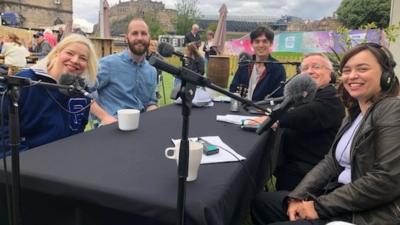 The podcast team at a table with microphones in Edinburgh