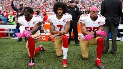 Colin Kaepernick kneeling with teammates in October 2016