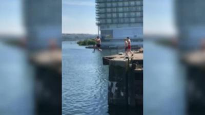 Man jumps off a ledge into water