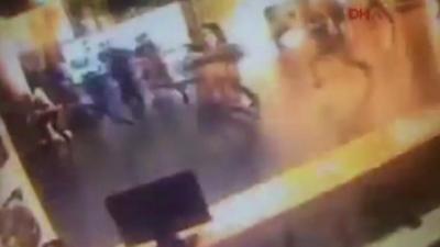 CCTV shows people running in the terminal as an explosion hits.