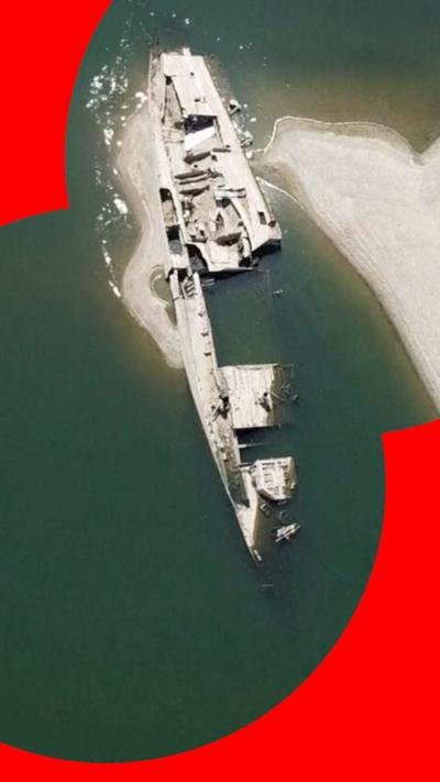 White-coloured remains of a ship sit in the Danube river.