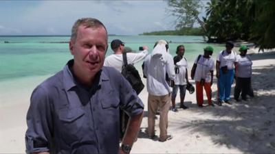 Andrew Harding stands on a beach