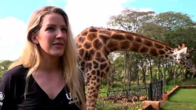 Ellie Goulding with a giraffe in the background