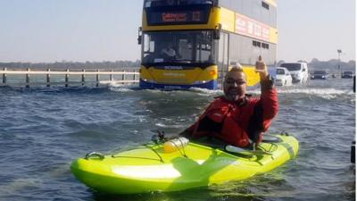 A kayaker found himself being pursued by a bus while kayaking over a road flooded by a high tide.