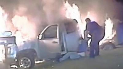 Police officer drags woman from burning car