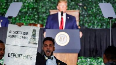 Protester holds sign at Trump speech