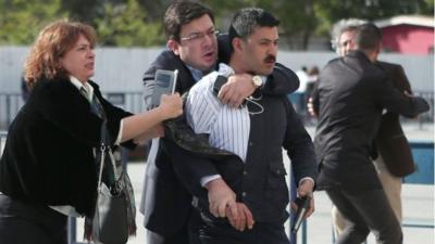 Dilek Dundar (L), the wife of editor-in-chief of Turkish newspaper Cumhuriyet daily Can Dundar, trying to stop a gunman as Can Dundar (R) is protected by another man on May 6, 2016 in Istanbul