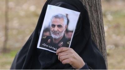 woman covers face with photo of Soleimani, Tehran