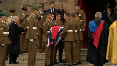 Pallbearers hold the coffin of Captain David Seath