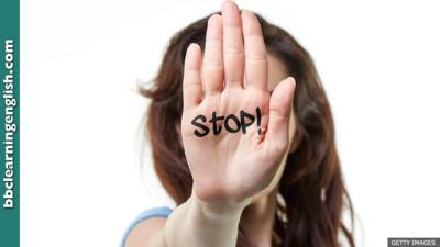 A woman holding up her hand. The word 'stop' is written on it