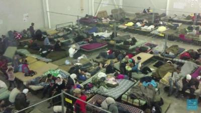 Migrants sleep in a detention centre