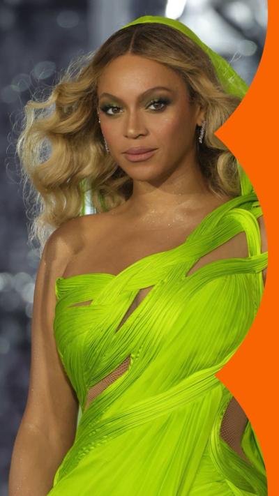 Beyonce stands on stage wearing a bright green sleeveless dress; she has wavy blonde hair