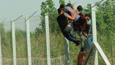 Afghan men breach the fence at Hungary's border